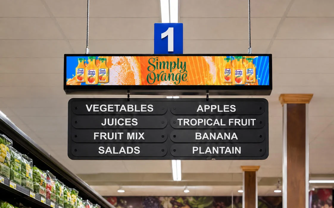 Ultra-wide LED bar screen running a juice advertisement above a supermarket produce aisle